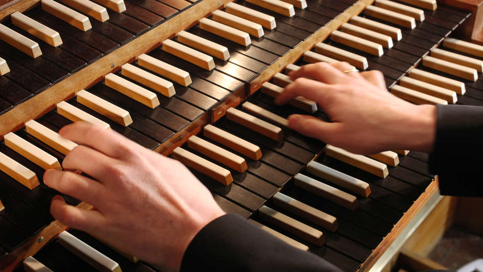 Hände eines Organisten auf den Tasten einer Orgel.