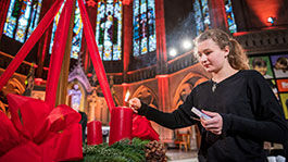 Junge Frau zündet Kerzen am Adventskranz in Kirche an