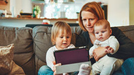 Mutter mit zwei Kindern auf der Couch beim Spielen