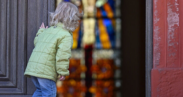 Mädchen schaut durch geöffnete Kirchentür in Kirche (Siegerfoto 2022)