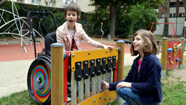 Zwei Schwestern spielen an einem Klangspiel auf einem inklusiven Spielplatz