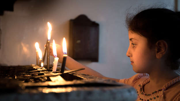 Ein Mädchen zündet eine Kerze an beim Gottesdienst der syrisch-orthodoxen Gemeinde „Marian al-Adra“ in Qamischli in Syrien.