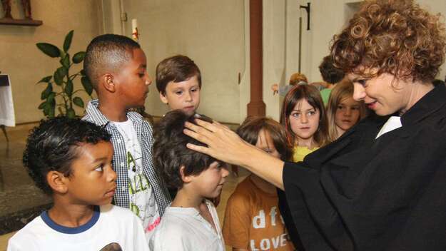 Bei einem ökumenischen Einschulungsgottesdienst in Frankfurt segnet Pfarrerin Pia Baumann die Kinder.