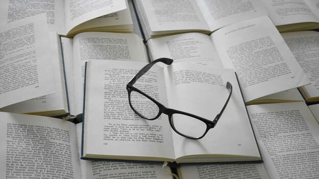 Aufgeschlagene Bücher mit Brille darauf