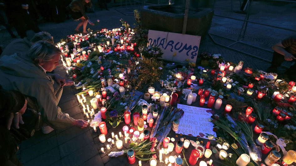 Menschen stellen Kerzen am Ort der Amokfahrt von Münster auf