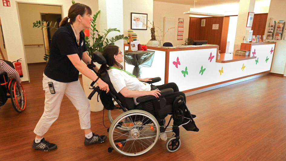 Pflegerin schiebt Pflegeheimbewohnerin im Rollstuhl