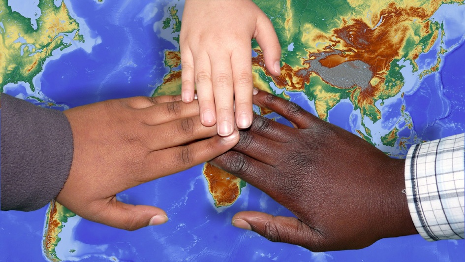 Drei Hände unterschiedlicher Hautfarbe liegen auf einer Weltkarte