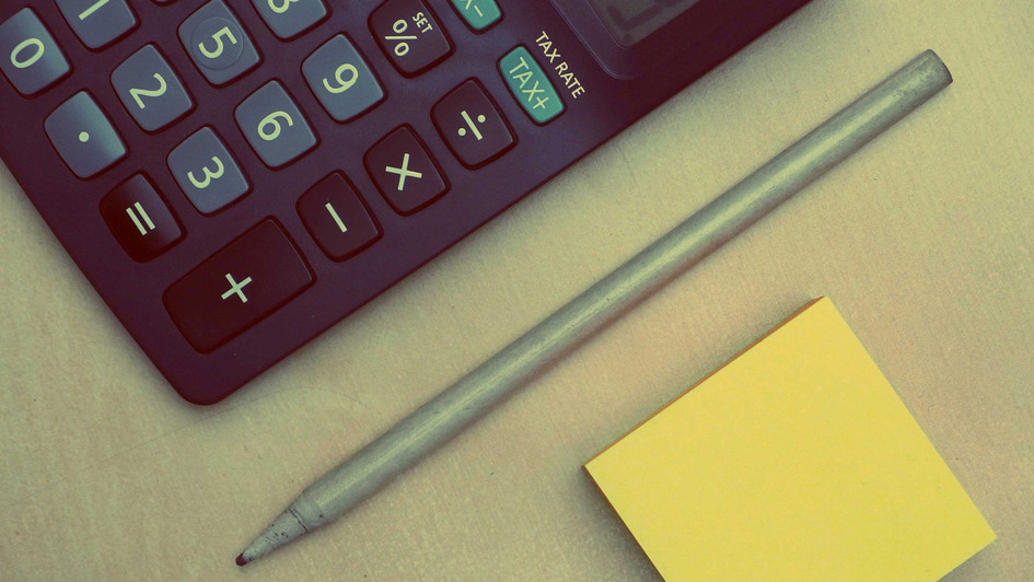 Taschenrechner, Bleistift und Notizblock auf einem Tisch