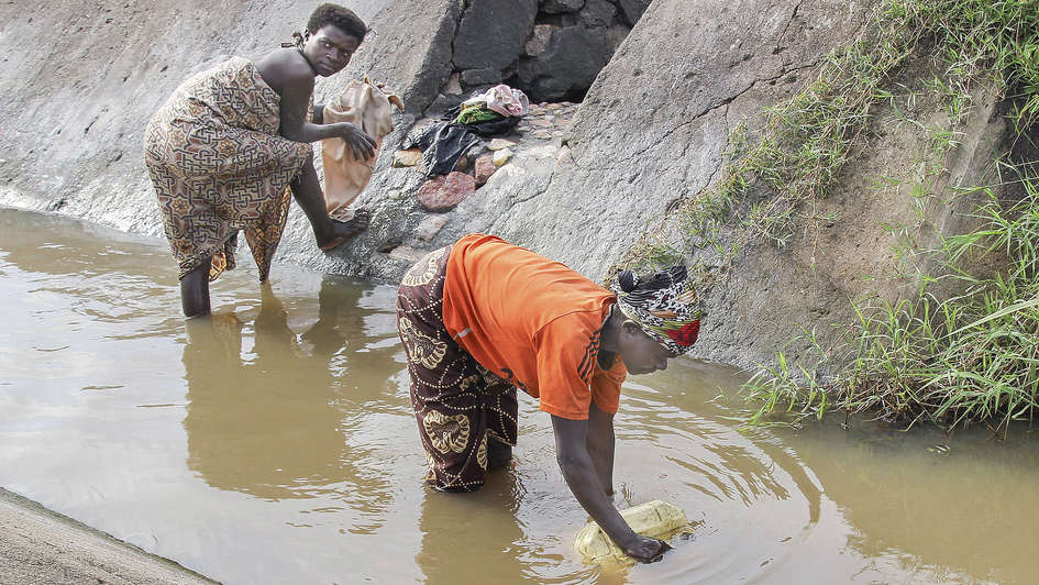Frauen schöpfen Wasser in einem Graben in Burundi