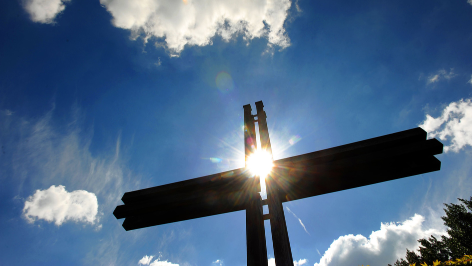Kreuz vor Hintergrund blauen Himmels und Sonne