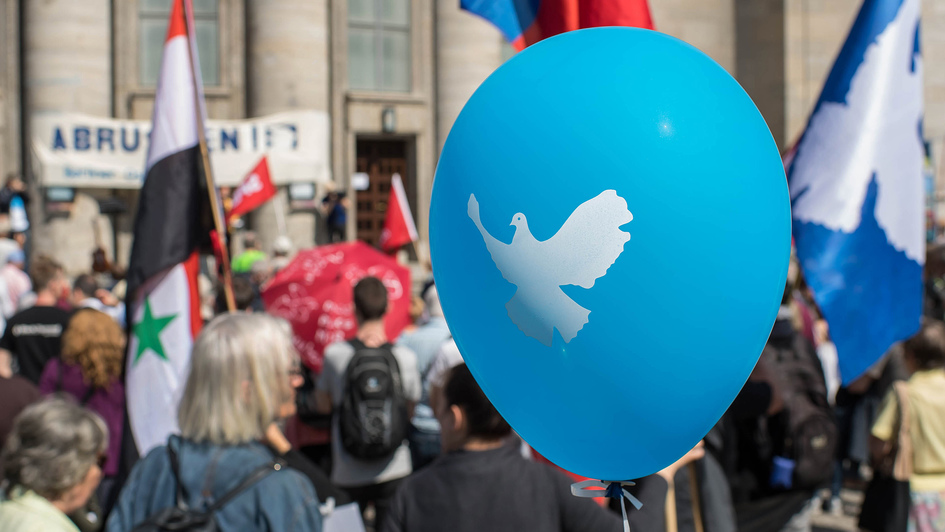 Demonstranten mit blauem Luftballon mit Friedenstaube beim Ostermarsch in Berlin Mitte