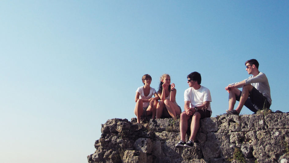 Junge Menschen sitzen auf einem Felsen