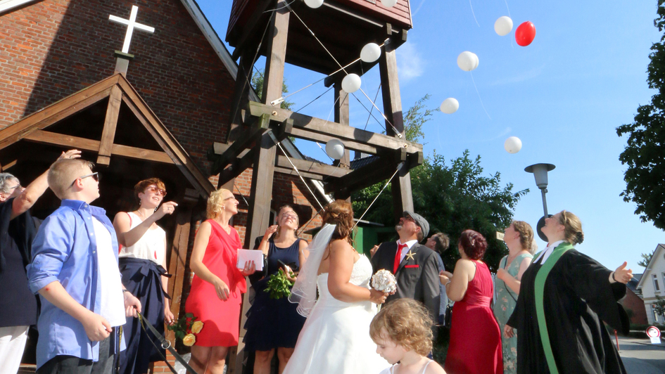 Hochzeitsgesellschaft lässt Luftballons hochsteigen vor der Urlauberkapelle in Cuxhaven-Duhnen