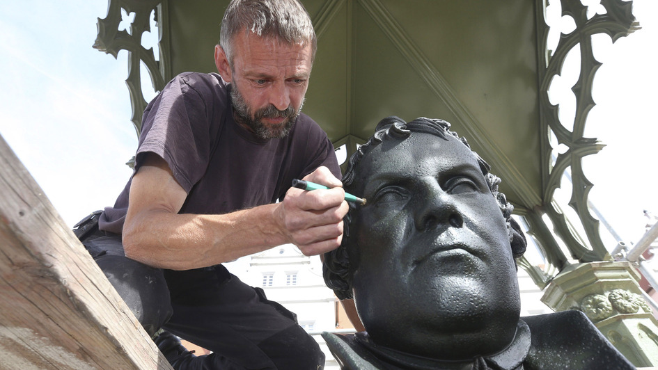 Ein Restaurateur säubert das Lutherdenkmal auf dem Wittenberger Marktplatz