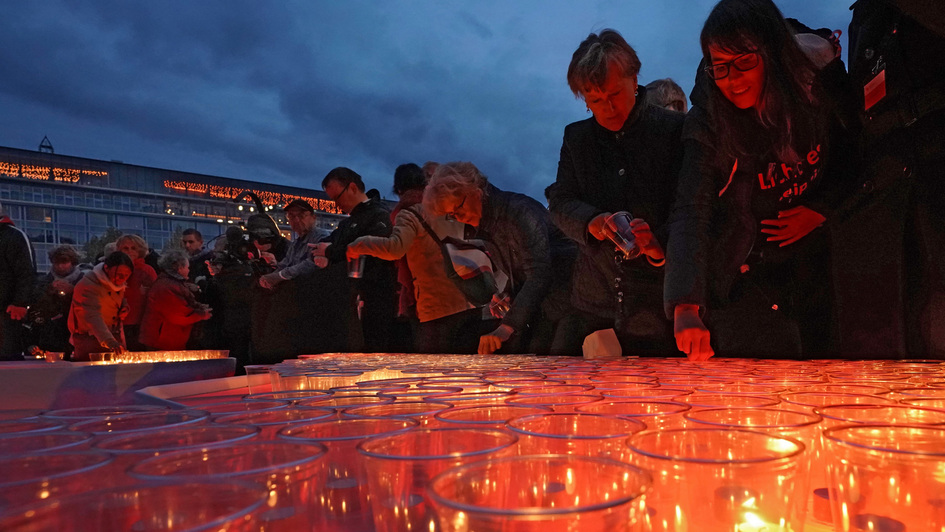 Menschen auf dem Leipziger Augustusplatz mit Kerzen, die eine funkelnde 89 formen, zum Gedenken an die Friedliche Revolution 1989