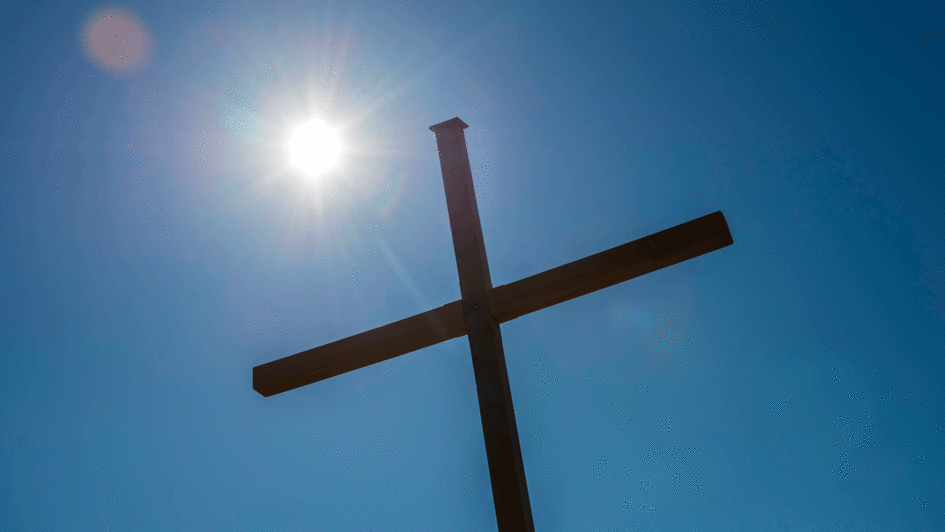 Symbolbild: Kreuz mit Sonne im Hintergrund