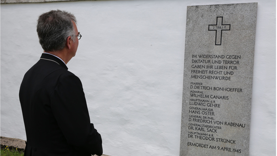 Der evangelische Militärbischof Sigurd Rink vor einer Gedenktafel für hingerichtete Widerstandskämpfer im den KZ-Gedenkstättte Flossenbürg