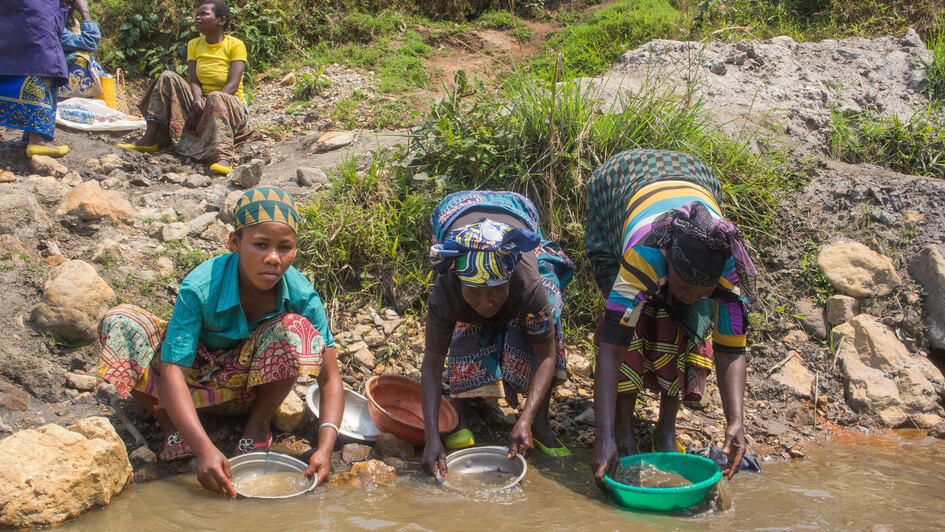 Frauen im Kongo waschen Zinnerz aus Gesteinen