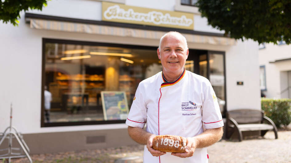 Baeckermeister Matthias Schwehr mit seinem Jubilaeumsbrot vor seiner Baeckerei in Endingen (Foto vom 04.09.2024). Ob Krusten-, Radler- oder Jubilaeumsbrot - jedes Brot von Matthias Schwehr hat eine Geschichte.