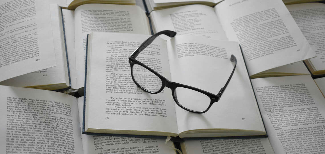 Aufgeschlagene Bücher und Brille darauf