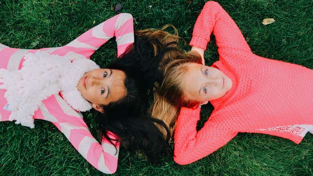 Zwei Mädchen liegen auf einer Wiese