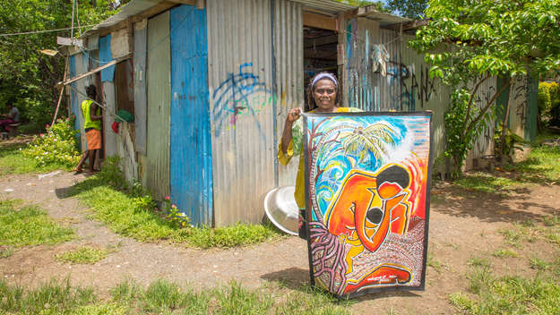 Künstlerin Juliette Pita mit dem Bild vor ihrer Hütte