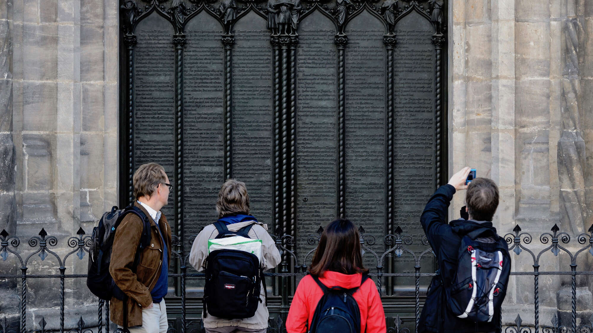 Besucherinnen und Besucher vor der Thesentür der Schlosskirche in Wittenberg